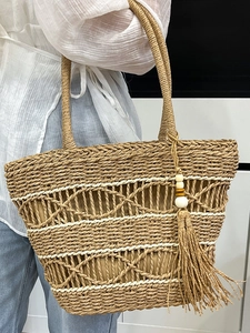 Handmade woven straw tote bag with tassel fringe for beach vacations and summer holidays