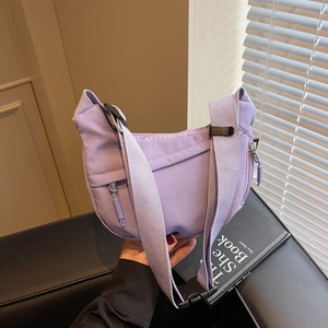 Detail view of purple nylon crossbody bag featuring wide strap with plastic buckle closure