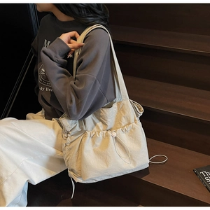 Detail of beige large tote bag showing side drawstring pockets and nylon texture
