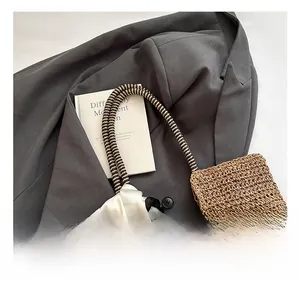 Close-up of a woven straw tote bag with black and white printed scarf and stylish handles