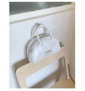 Dettaglio della borsa tote bianco perlato con toppa grafica e anello a D in metallo