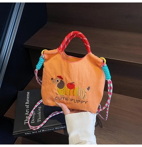 Close-up of orange bucket bag with cute dachshund embroidery and colorful braided handle