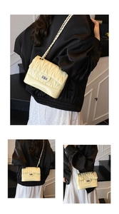 Detailed view of yellow quilted leather bag with V-shaped stitching and silver metal lock