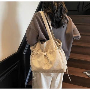 Close-up of lightweight beige tote bag showing drawstring pockets and nylon fabric texture