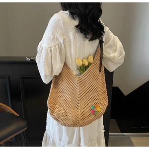 Detail of woven beach tote with colorful flower knit charm and sleek black leather strap