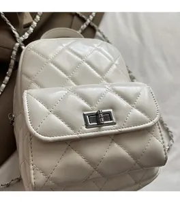 Macro shot of cream white quilted leather backpack showing diamond texture and chain strap