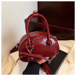Detail of glossy dark red bowling bag with polished finish and beaded charm decoration