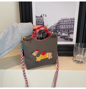Close-up of dachshund embroidery and woven straps on brown canvas bucket bag