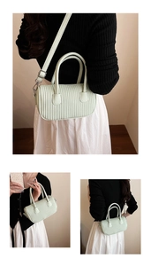 Detailed view of pale green cylindrical handbag featuring vertical quilted texture