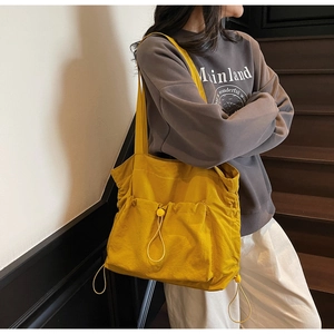Detail of yellow nylon tote bag featuring functional drawstring pockets and large capacity