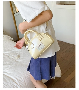 Détail d'un mini sac bandoulière blanc crème avec étiquette logo rétro et bandoulière fine