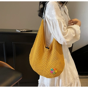 Close-up of yellow knitted tote bag featuring a colorful crochet flower detail