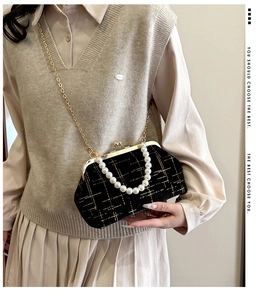 Détail du sac coquille en velours noir avec lignes dorées et poignée en perles