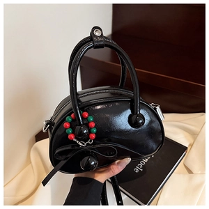 Detailed close-up of glossy black bowling bag featuring a colorful beaded charm accessory
