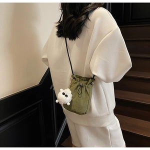 Army green nylon drawstring crossbody bag shown with a cute white monster plush charm
