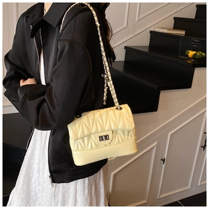 Detail of cream yellow quilted shoulder bag with silver turn-lock and chain strap