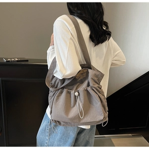 Detail of grey tote bag with white drawstring buckle and natural textured fabric