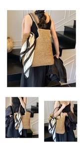 Detail view of large straw tote bag with woven texture and striped scarf on stairs
