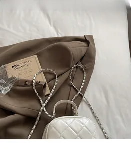 Detail of white quilted leather mini backpack with silver chain strap and top handle