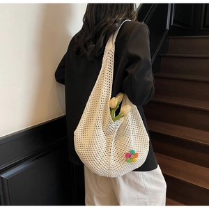 Detail of white crochet tote bag with colorful flower patch and hollow knitted texture