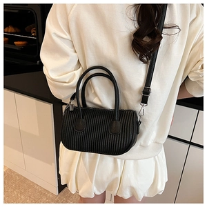 Detail of black pleated texture on mini round handbag with silver hardware and dual handles