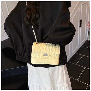 Detail view of a cream quilted crossbody bag with silver chain and metal twist lock
