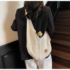 Detail of white crochet shoulder bag with colorful floral patch for summer beach use