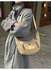 Detail of beige nylon crescent bag with woven zipper pulls and wide strap