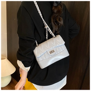 Close-up of quilted light blue leather crossbody bag with chain strap and metal lock
