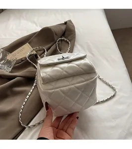Detailed close-up of white quilted PU leather backpack with gold chain strap and metal lock