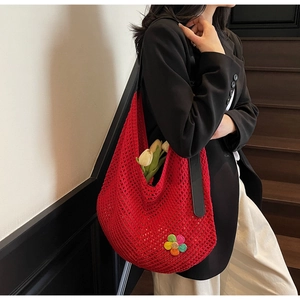 Detail view of red crochet tote bag with black strap and colorful floral patch accent