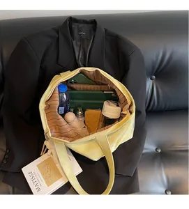 Spacious interior of light yellow tote bag featuring striped lining and zip pocket