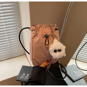 Detail of pink drawstring crossbody phone bag with cute white plush monster charm