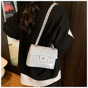 Detail of silver chain crossbody bag with V-quilt pattern and metallic square lock