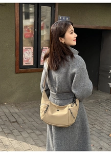 Detail of khaki canvas dumpling crossbody bag with side zipper pocket on a model