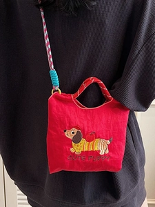 Red canvas bucket bag with embroidered dachshund puppy and colorful woven strap