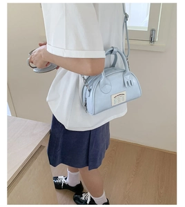 Détail du sac bowling bleu clair avec étiquette vintage et attaches de poignées uniques
