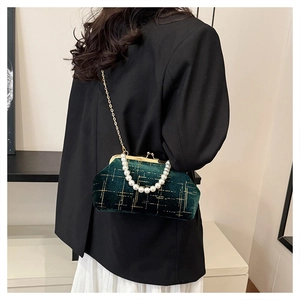 Détail d'un sac de soirée en velours vert foncé avec poignée en perles et chaîne dorée