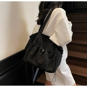 Close-up of black drawstring tote bag detail showing nylon texture and side buckle