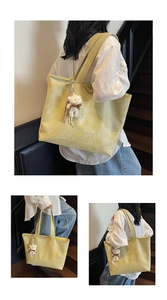 Detail of light yellow tote bag with embossed logo and cute white plush bear pendant
