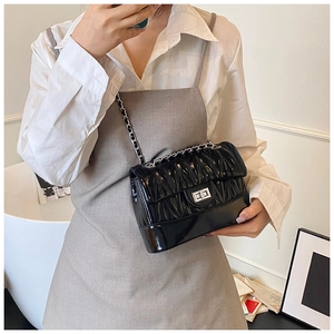 Close-up of black quilted leather crossbody bag with silver twist lock and chain strap