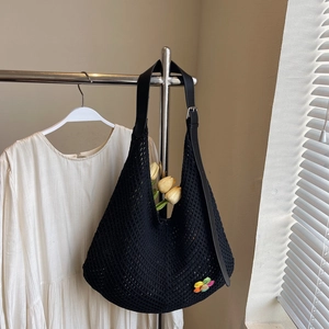 Close-up of black crochet knit tote bag with leather strap and colorful flower detail