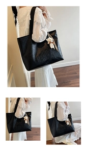 Detail of black faux leather tote bag with embossed logo and plush bear pendant accessory