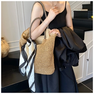 Detail of hand-woven straw tote bag with black and white striped scarf and wrap handles