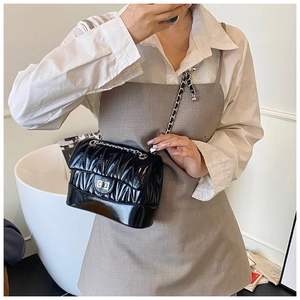 Close-up of a stylish black quilted chain bag with a silver rotating metal lock clasp