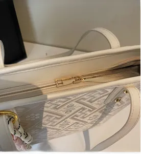 Detail of smooth gold metal zipper and jacquard fabric texture on the beige tote bag