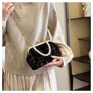 Détail du sac coquille en velours noir avec anse en perles et chaîne dorée sur mannequin