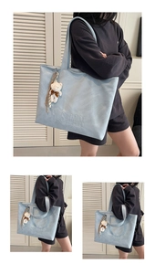 Detail view of light blue tote bag with H.SHAN logo embossing and plush bear charm decor