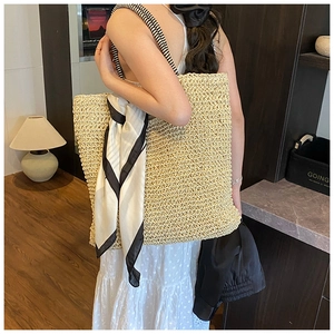 Large hand-woven straw tote bag with striped handles and decorative scarf detail