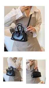 Detail view of black heart-shaped buckle bag with round handles and crossbody strap